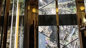 Un ascensor de vidrio con vista a un terreno rocoso al aire libre.