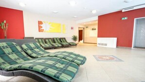 A lobby with green and black checkered lounge chairs, a white wall with a sunburst artwork, and a red accent wall. - Falkner by Interhome (Längenfeld)