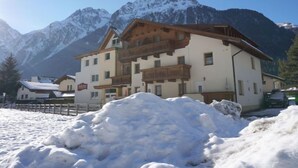 A hotel with a wooden facade and balconies, set against a backdrop of snow-covered mountains. - Falkner by Interhome (Längenfeld)