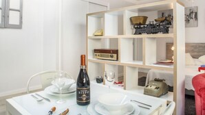 A dining area with a table set for two, a bottle of wine, and a vintage radio on a shelf. - Studio Mafra by Interhome (Mafra)