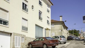 A street with parked cars and a building with multiple windows and shutters. - Studio Mafra by Interhome (Mafra)