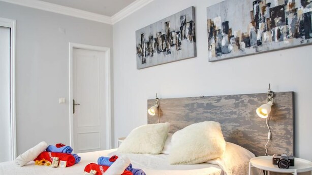 A bedroom with a bed, two pillows, a bedside table with a camera, and abstract art on the wall. - Studio Mafra by Interhome (Mafra)