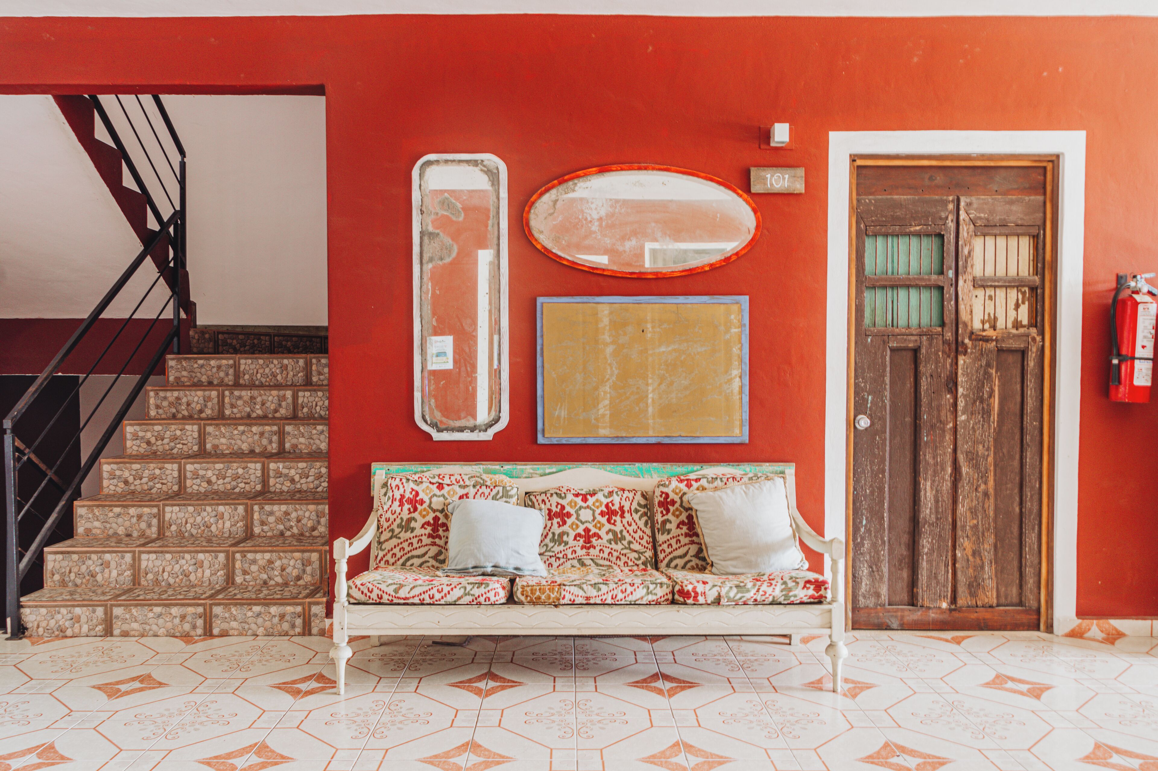 Una habitación con un sofá blanco, una puerta de madera y una escalera.