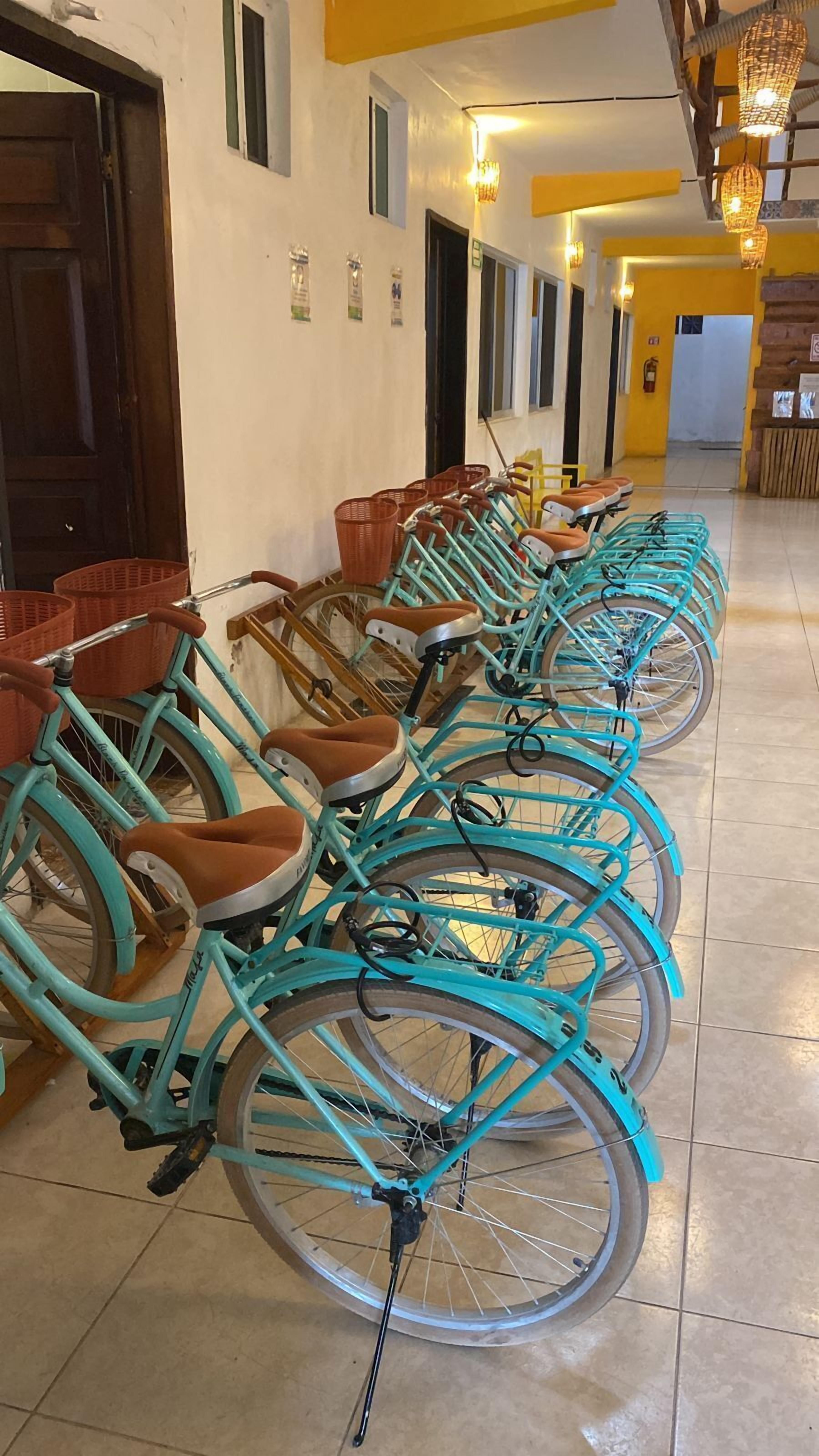A row of turquoise bicycles with brown seats parked indoors, likely in a hotel lobby.