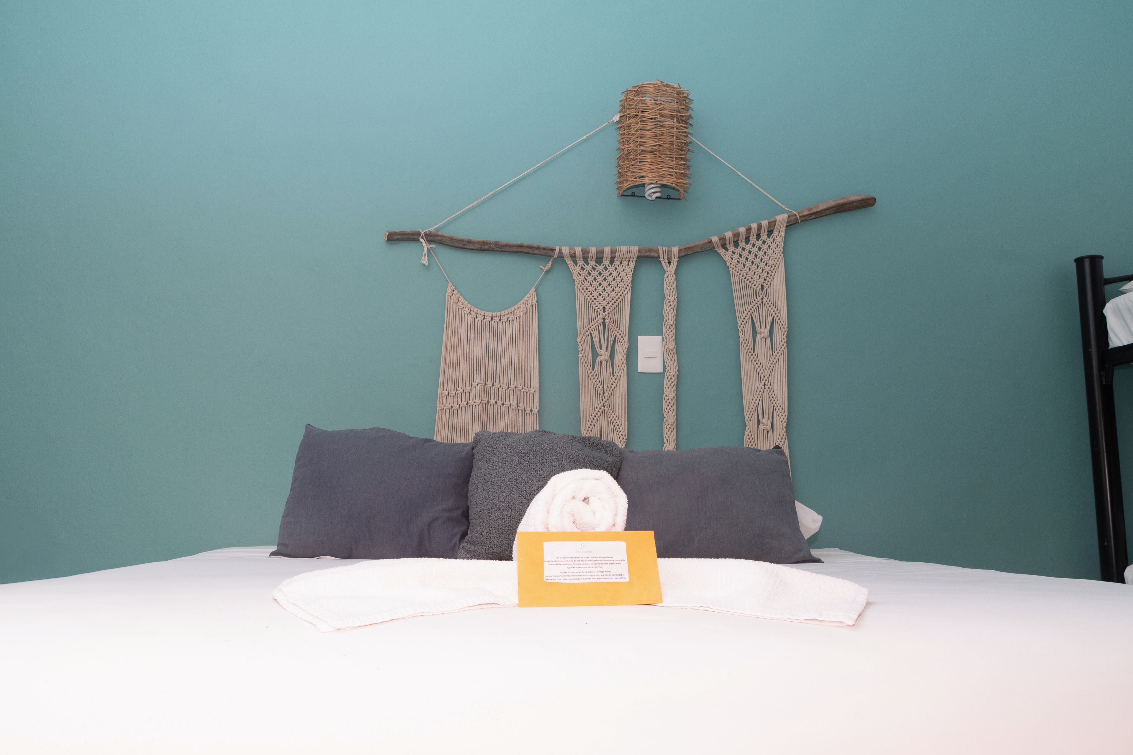 A bed with a white comforter, grey pillows, and a yellow sign on the bed.