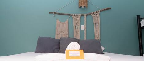 A bed with a white comforter, grey pillows, and a yellow sign on the bed.
