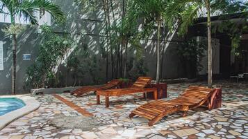 A pool area with lounge chairs and a mosaic-tiled floor.