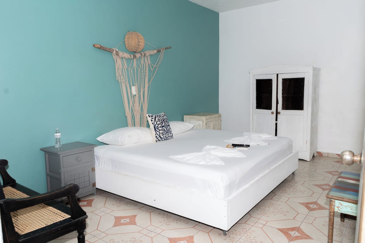 A bedroom with a bed, a nightstand, a chair, and a wardrobe.