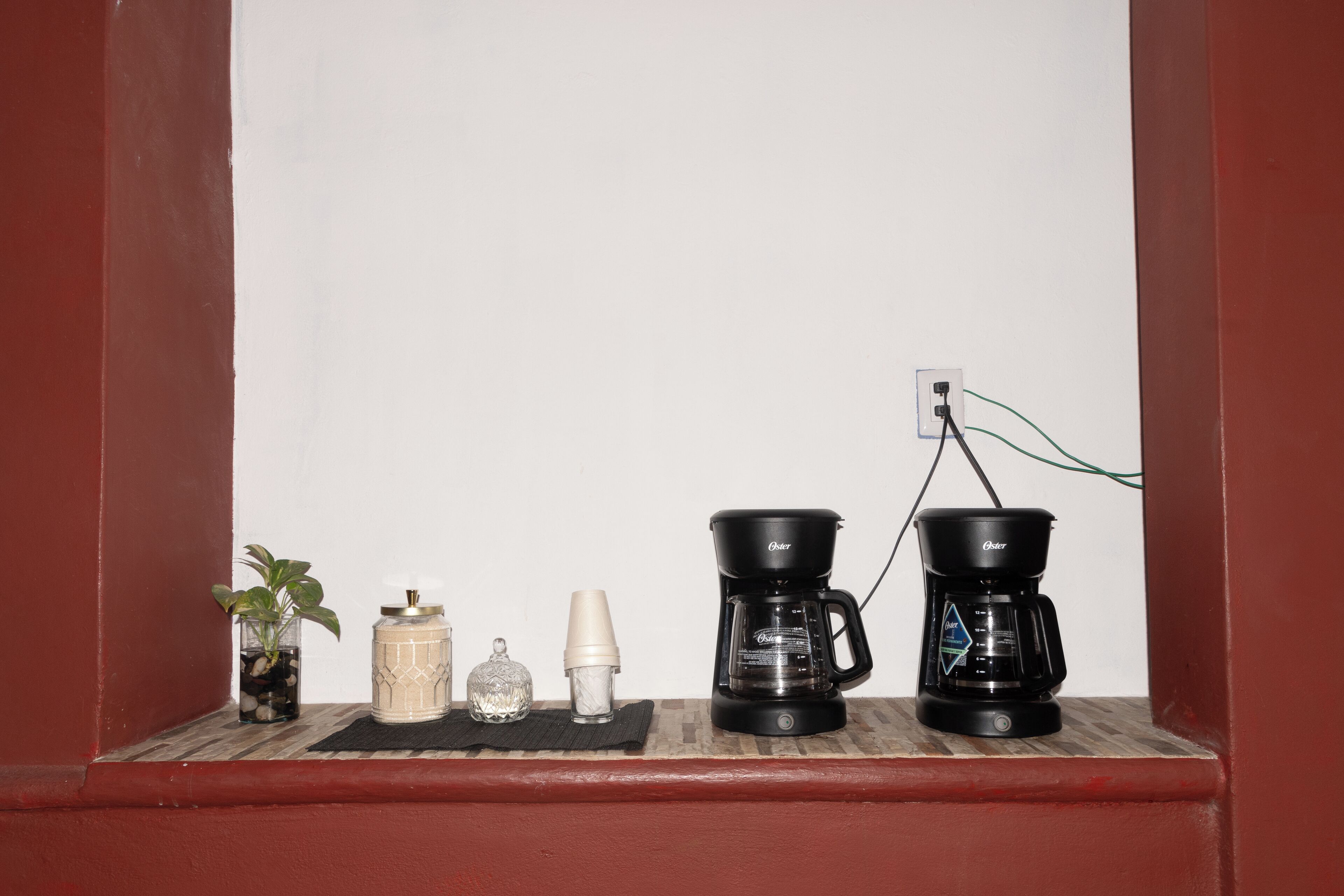 Una estantería con una planta en maceta, un salero, un azucarero y dos cafeteras.