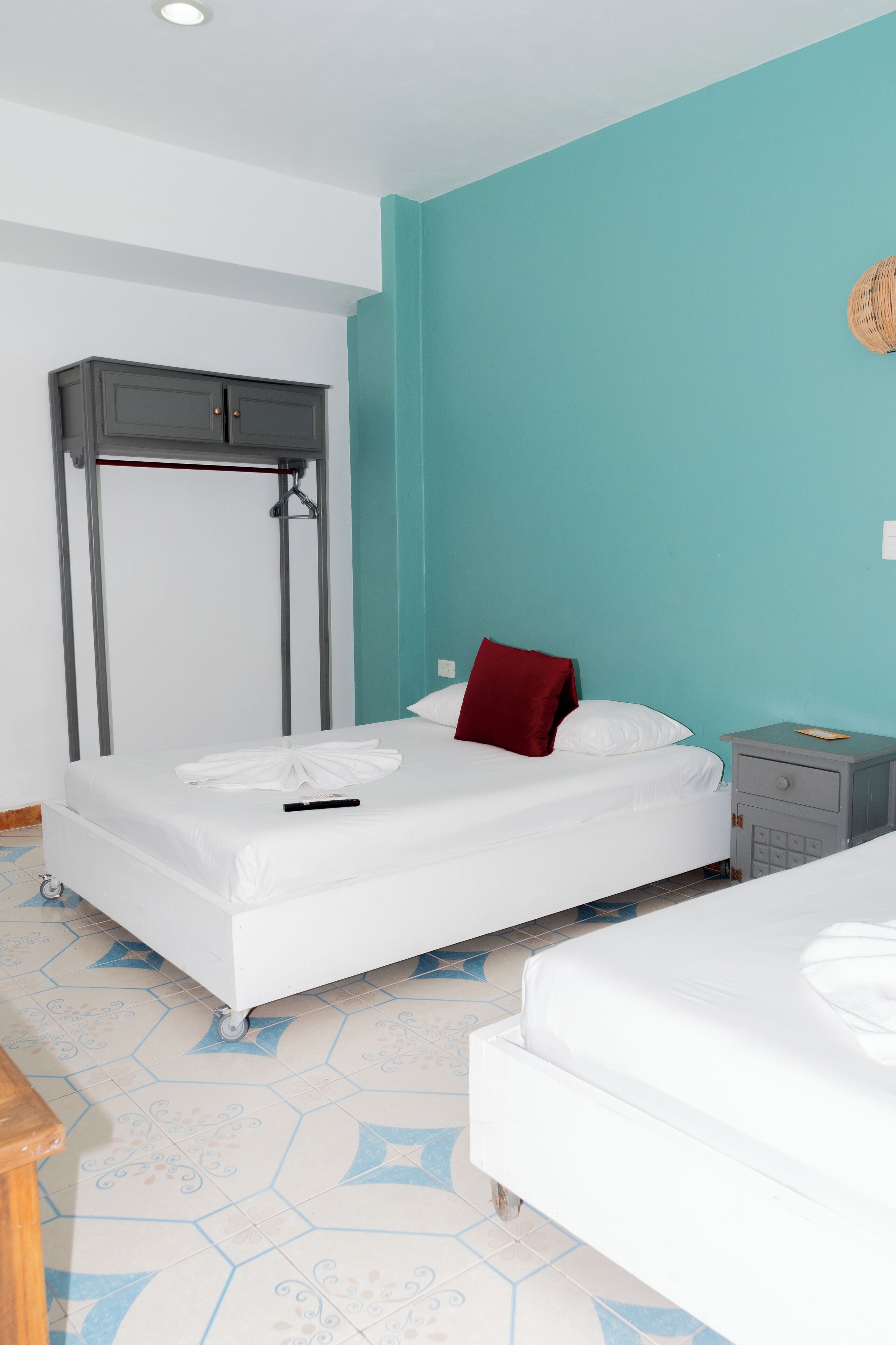 A hotel room with a bed, a nightstand, a wardrobe, and a tiled floor.