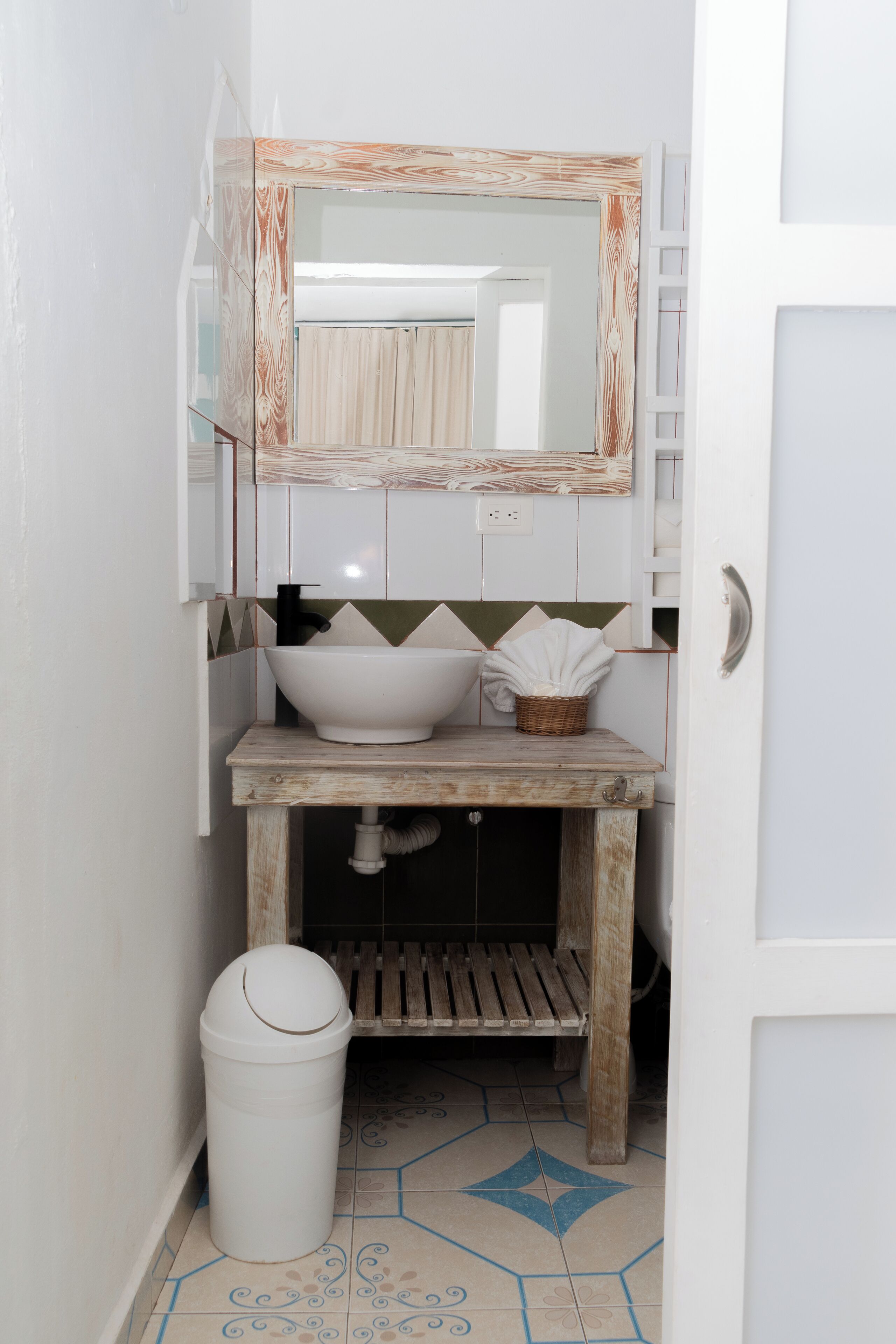 Une salle de bain avec un lavabo blanc, un meuble-lavabo en bois et un miroir avec un cadre en bois.