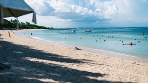 A beach with clear blue water, boats, and umbrellas. - Villa Katara (Seminyak)