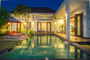Une maison moderne dotée d’une piscine, d’un espace salon extérieur et d’une entrée bien éclairée.