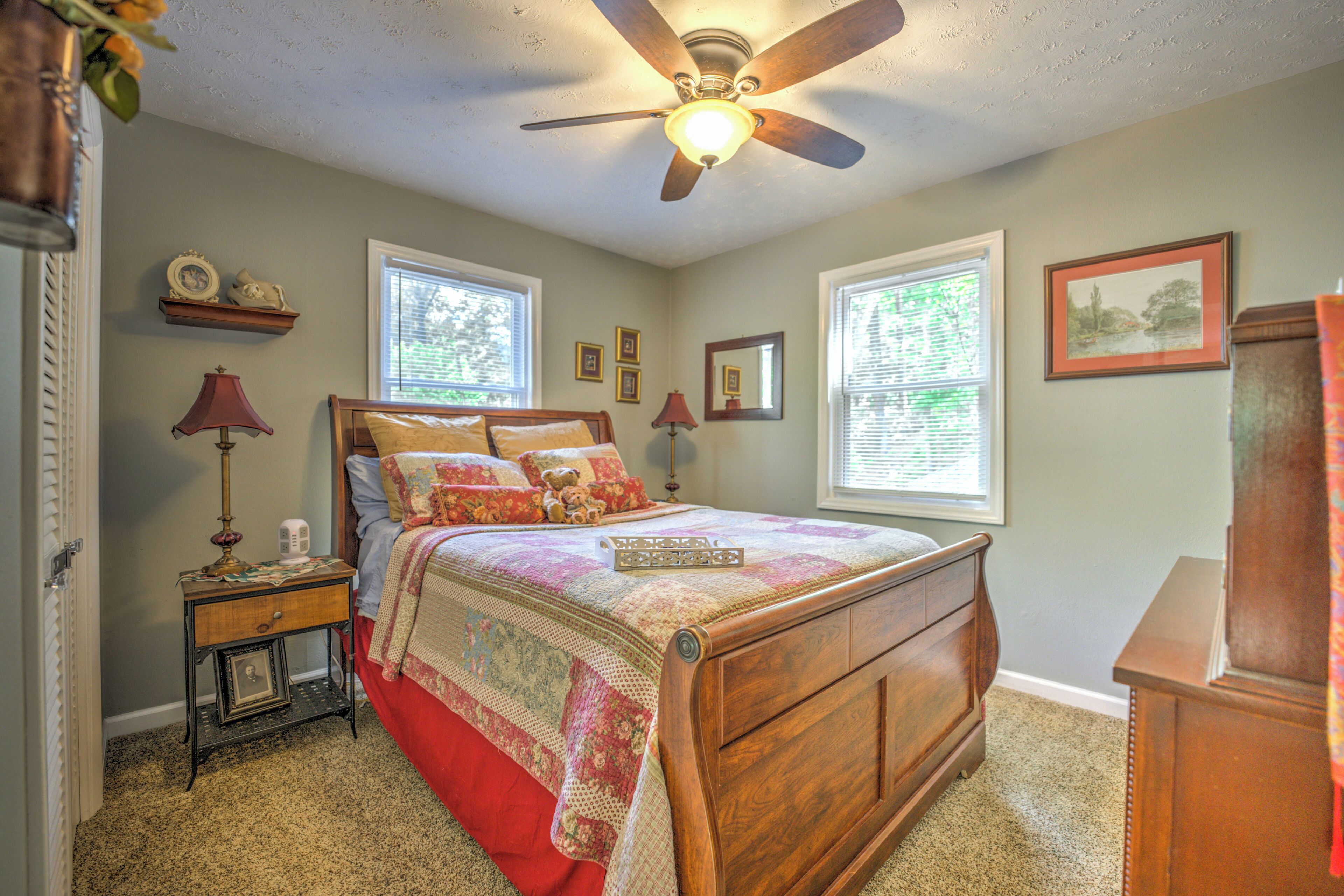 A bedroom with a wooden bed, a ceiling fan, and a window with blinds.