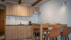 Eine Küche mit Holzschränken, einer Arbeitsfläche und einem Essbereich mit Hockstühlen.