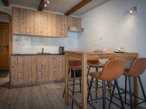 A kitchen with wooden cabinets, a countertop, and a dining area with stools.