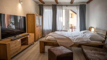 Ein modernes Schlafzimmer mit einem hölzernen Bett, einem Fernseher auf einem Holzschrank, einem Holzschrank und Blick auf einen Balkon.