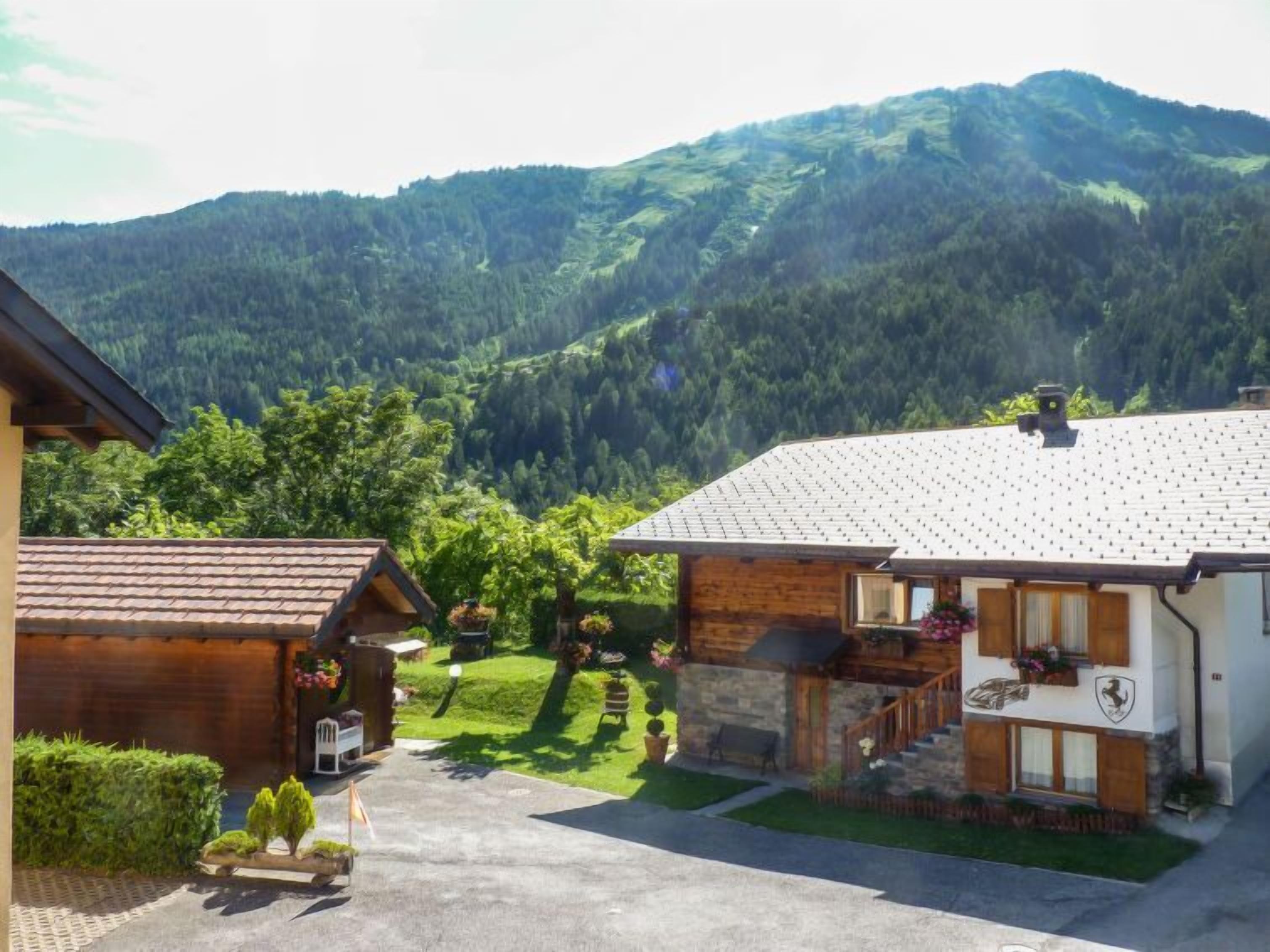 Un chalet de montagne à l’extérieur en pierre et en bois, avec une allée pavée et une pelouse bien entretenue.