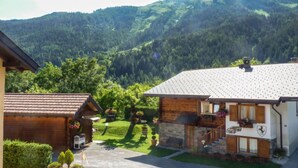 Ein Berggasthof mit Steinfassade und Holzelementen, einer gepflasterten Auffahrt und einem gepflegten Rasen.