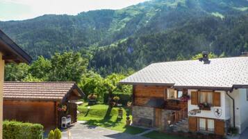Un chalet de montagne à l’extérieur en pierre et en bois, avec une allée pavée et une pelouse bien entretenue.