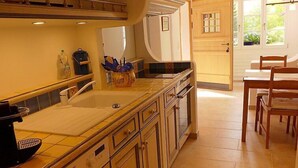 Una cucina con una grande isola, forno a incasso e zona pranzo con sedie di legno.