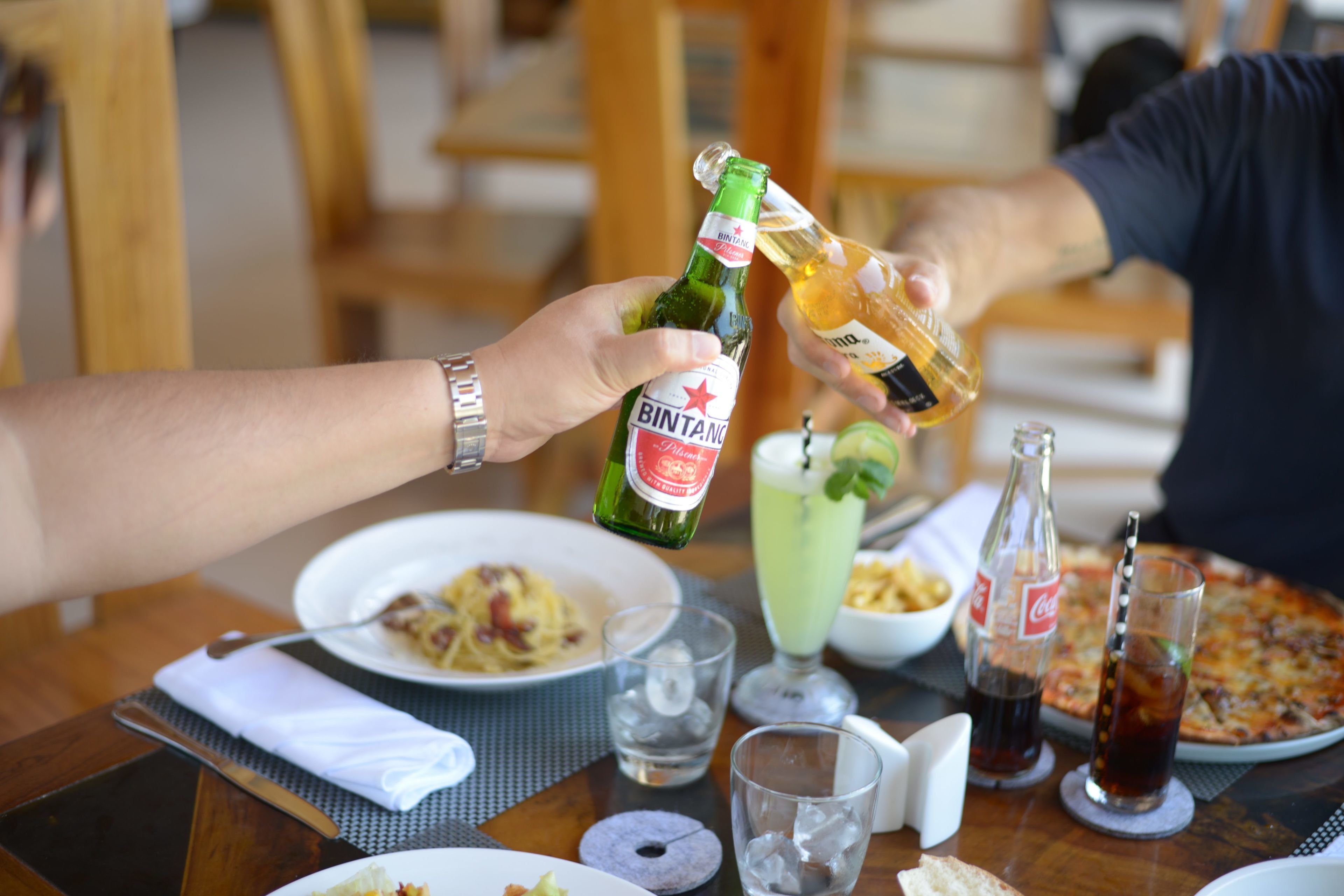 Una mesa de comedor con platos de comida, bebidas y una botella de cerveza Bintang.