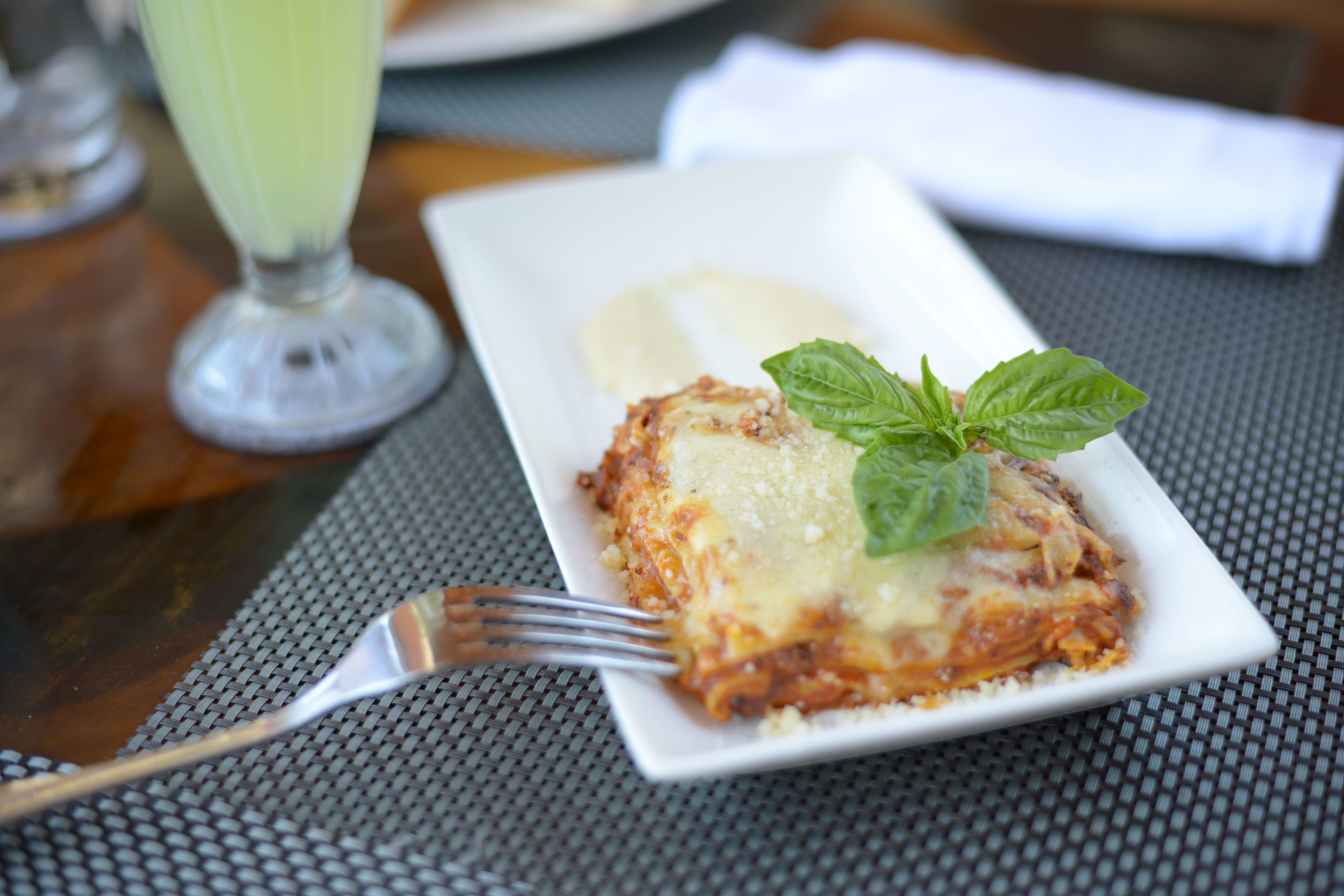 Een bord lasagna met een vork op een tafel.