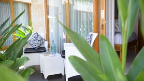 A sunlit room with a white wicker sofa, a small side table, and a glass of water. - Villa Casablanca Surf Keramas (Gianyar)