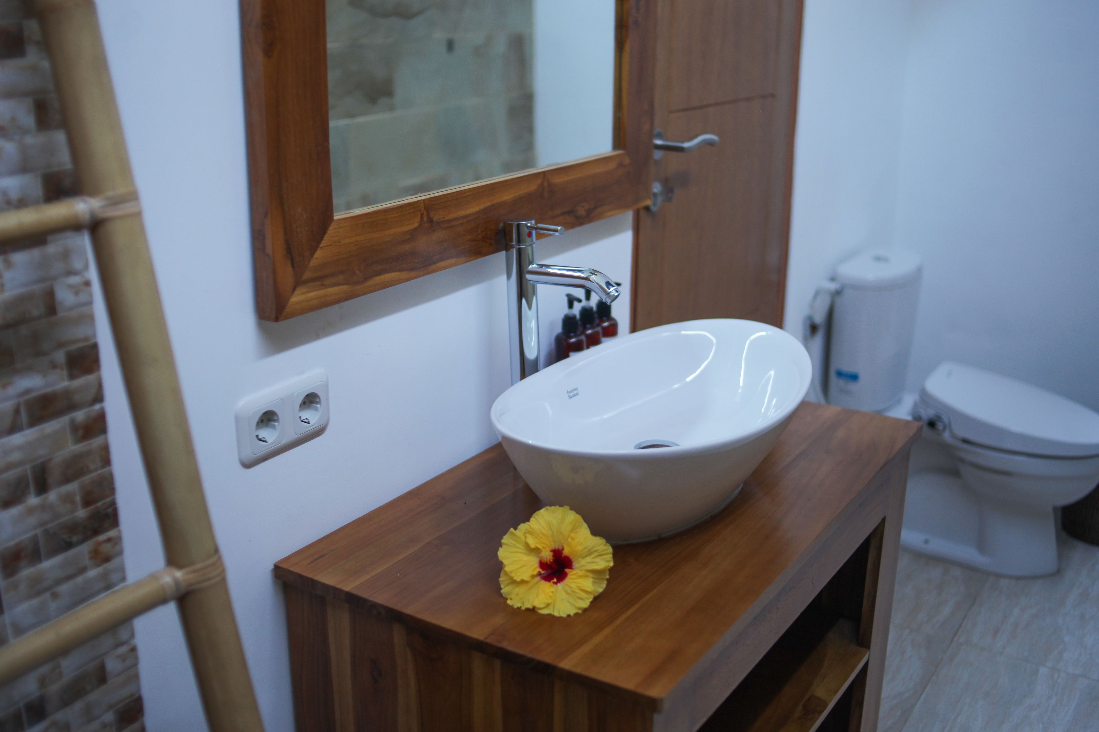 A bathroom with a wooden vanity, a white sink, and a mirror.