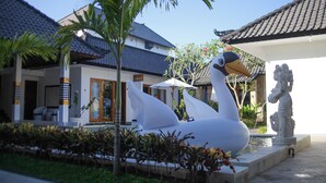 A swan statue in a landscaped area with a building in the background. - Villa Casablanca Surf Keramas (Gianyar)