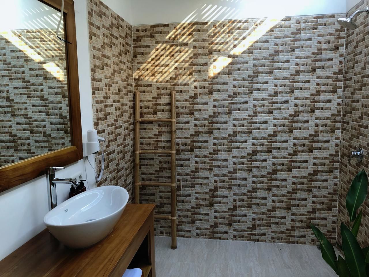 Ein Badezimmer mit einem Holzkosmetikschrank, einem weißen Waschbecken und einer Duschkabine mit einer Holzleiter.