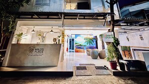 Un edificio de dos pisos con recepción, un mural y plantas en macetas.