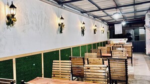 Un restaurante con mesas y sillas de madera, paredes verdes y faroles colgantes.