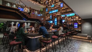 Een moderne bar met verschillende zitmogelijkheden en een trap naar een hoger niveau.