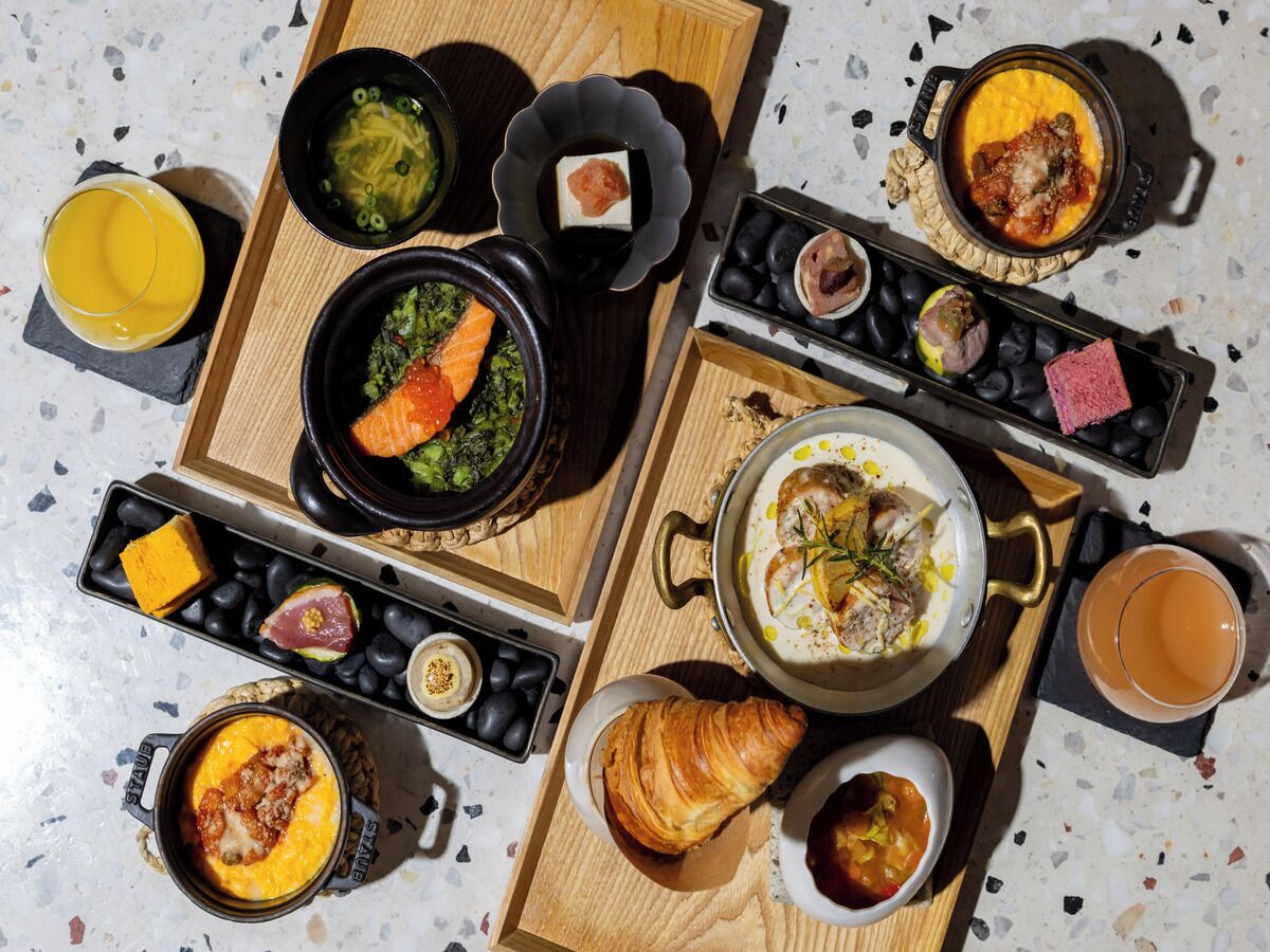 A breakfast spread with various dishes and drinks on a wooden table.
