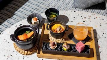 Una mesa con varios platos, incluyendo salmón, una olla de sopa y una bandeja con aceitunas y carne.