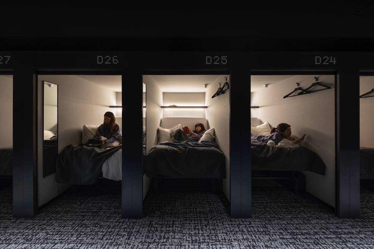 Une chambre d’hôtel avec trois lits, chacun étant identifié par un numéro (D26, D25, D24).