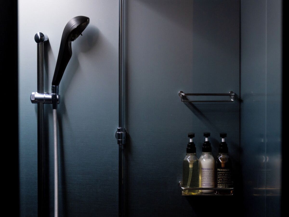 Une salle de bain avec une douche, un porte-serviettes et une étagère contenant des articles de toilette.