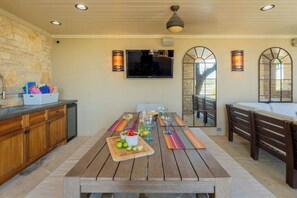 A dining area with a wooden table, chairs, and a TV mounted on the wall.