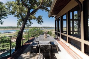 Un espacio de estar al aire libre techado con una mesa y sillas, con vistas a un cuerpo de agua y el paisaje.