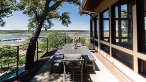 Un espacio de estar al aire libre cubierto con mesa y sillas, con vistas a un paisaje pintoresco.
