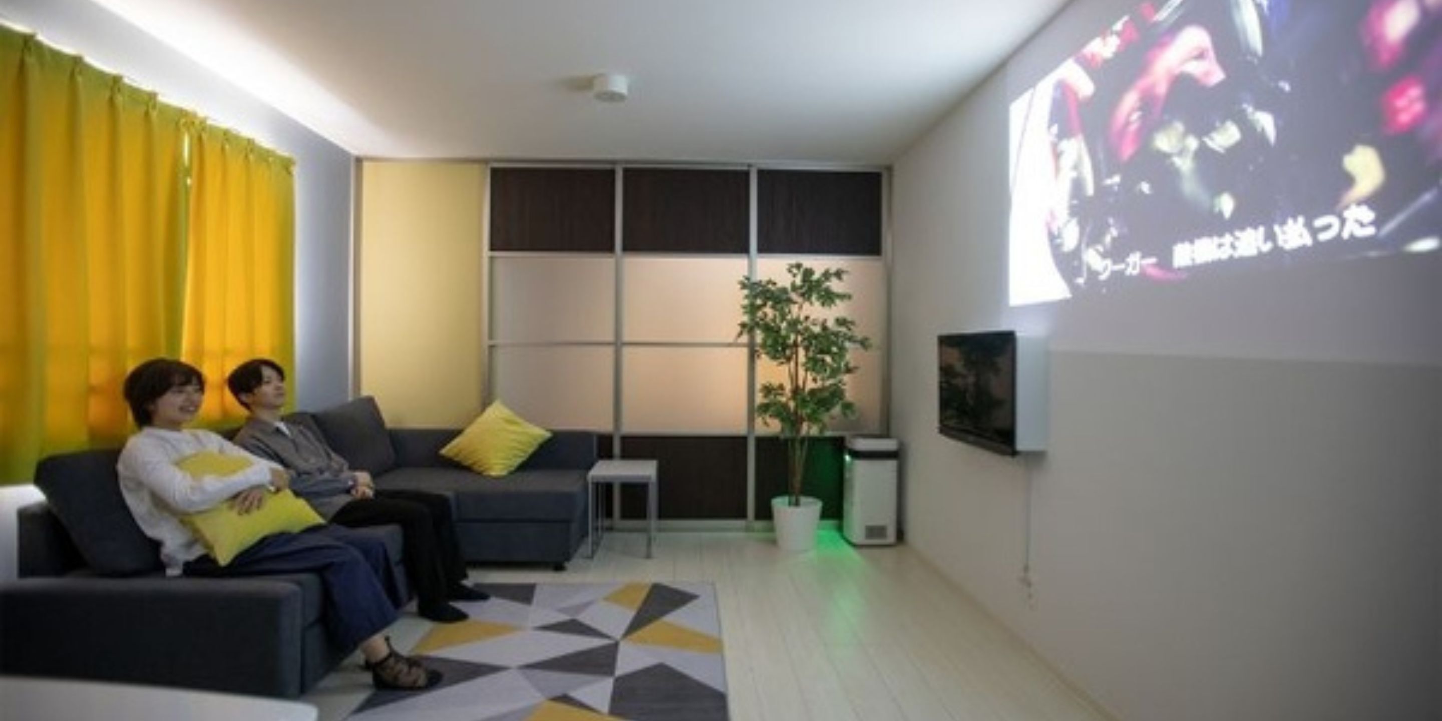Een moderne woonkamer met een bank, een bijzettafeltje, een plant en een tv-scherm waarop een afbeelding wordt weergegeven.