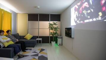 Een moderne woonkamer met een bank, een bijzettafeltje, een plant en een tv-scherm waarop een afbeelding wordt weergegeven.