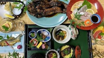 A variety of dishes including grilled fish, sashimi, and other seafood, arranged on a wooden table.