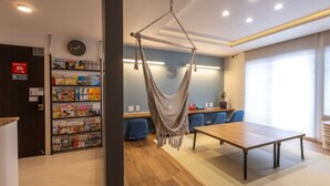 Una habitación moderna con una hamaca, una mesa de madera y una zona de estar con sillas azules.