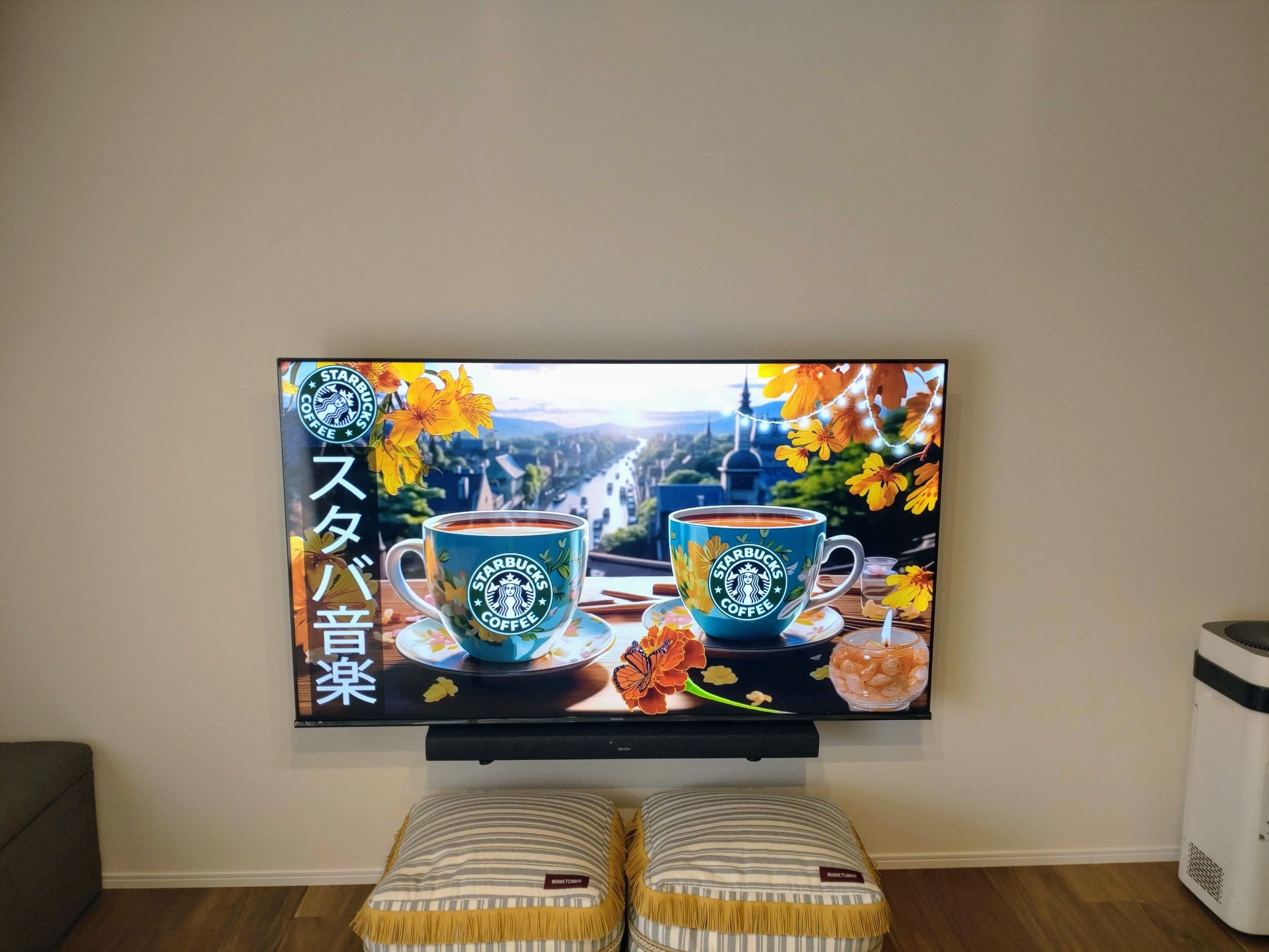 A television displaying a Starbucks Coffee advertisement with two cups of coffee, a bowl of snacks, and a scenic background.