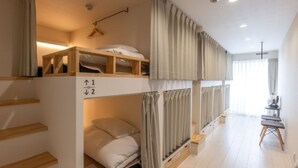 Habitación con literas, una escalera de madera, un escritorio y una silla.