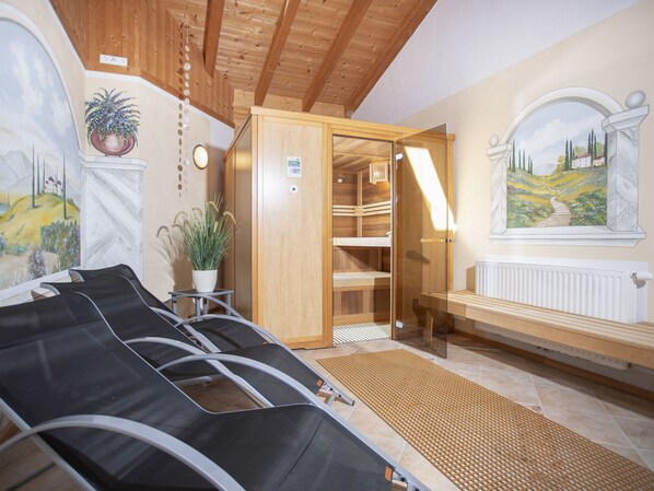 A sauna room with wooden benches, a radiator, and a painting of a landscape.