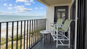 A balcony with a view of the beach, two chairs, and a small table. - Panoramic View DIRECT OCEANFRONT Unit at Summer Winds. Multiple pools, hot tubs (Indian Beach)