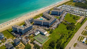 An aerial view of a coastal hotel with multiple buildings, a beach, and a parking lot. - Panoramic View DIRECT OCEANFRONT Unit at Summer Winds. Multiple pools, hot tubs (Indian Beach)